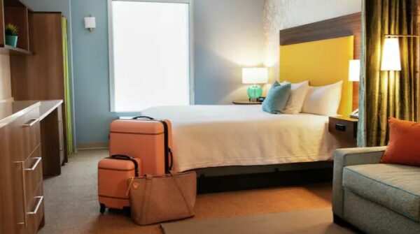 a hotel room with a bed, couch and luggage