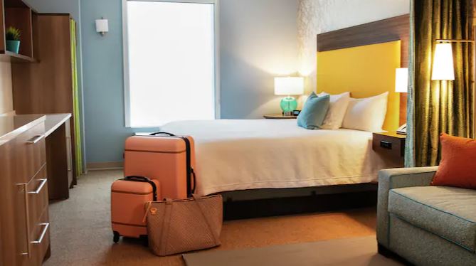 a hotel room with a bed, couch and luggage