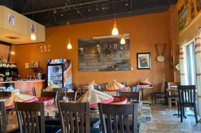 a restaurant with tables, chairs and pictures on the wall