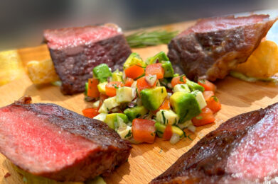 a wooden cutting board topped with meat and veggies