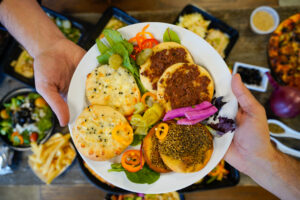 a person holding a plate of food on top of a table
